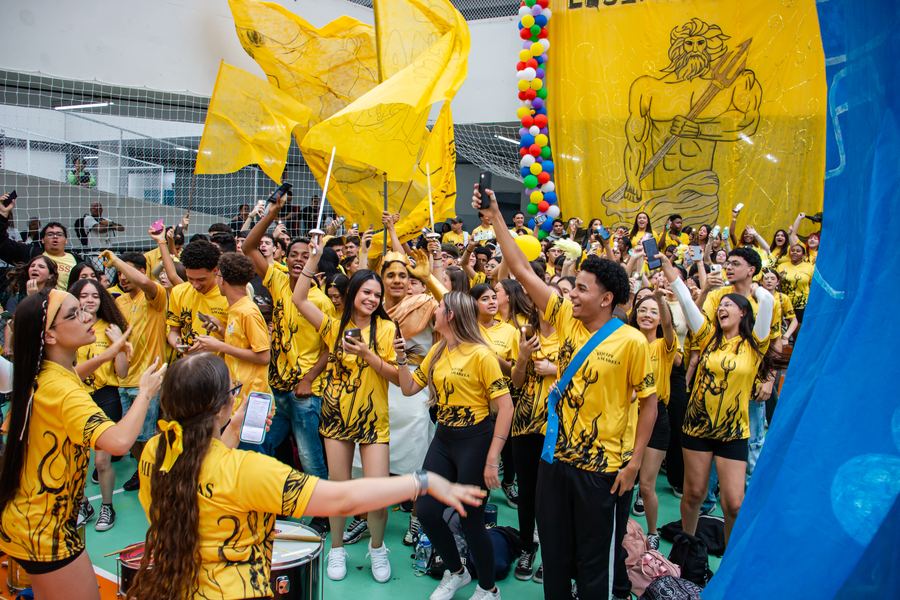 Equipe Amarela reunida com bandeiras douradas na quadra da escola